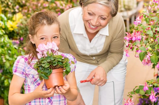 Grandmother and granddaughter holding purple potted cyclamen at garden centre