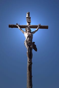 Statue of Jesus Christ on a cross. Blue sky in the background. Vertically.