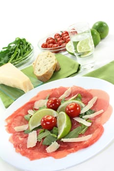 a plate of carpaccio with parmesan,lime and arugula
