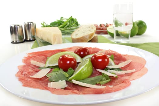 a plate of carpaccio with parmesan,lime and arugula