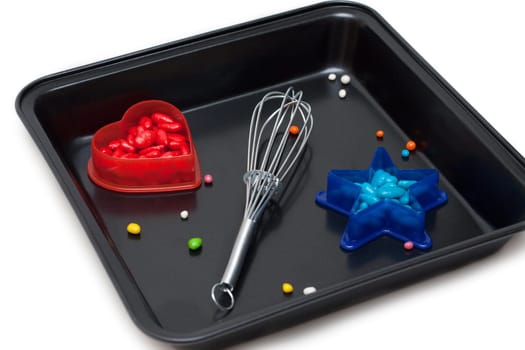 Form for baking, plastic red heart with sweetmeat and blue star, on white background