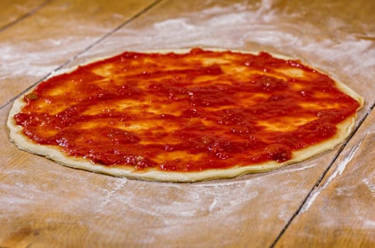 raw pizza base with tomato sauce