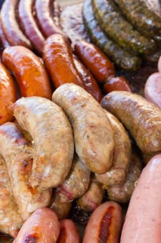 Assorted grilled types of sausages ready for sale at a farmer's market.