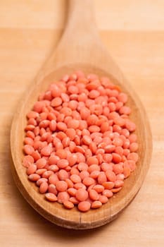 Close-up of red lentils on a wooden spoon