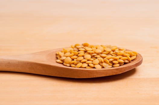 Close-up yellow lentils on a wooden spoon