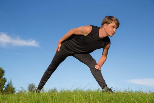 Sportsman making exercise movement to stretch one leg