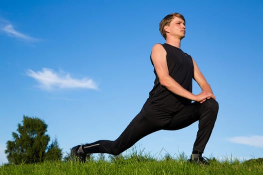 Sportsman making exerxise mowements to stretch both legs