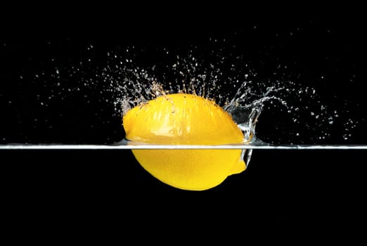 Fresh lemon falling into water isolated on black background