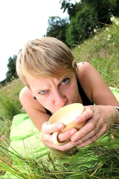 girls is drinking from a cup on a meadow