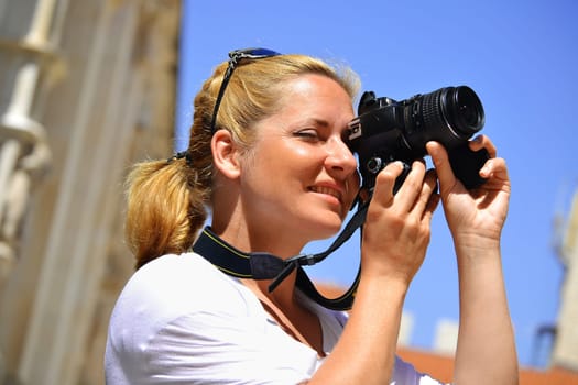 Young female tourist visiting Mediterranean old town on vacation. Woman taking photos on the street