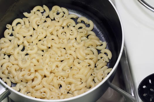 Finished pasta in a pan on the stove ready to add ingredients to.
