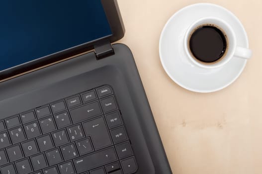 Closeup of Notebook Computer and Cup of Coffee on Wooden Table