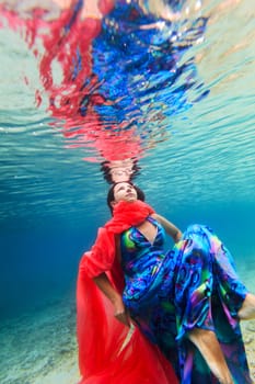 Young beautiful woman in blue dress underwater
