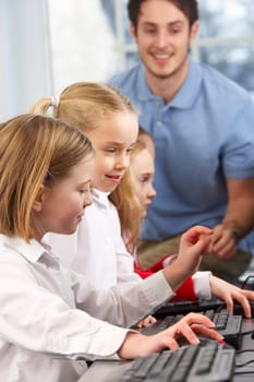 Girls using computers in class with teacher