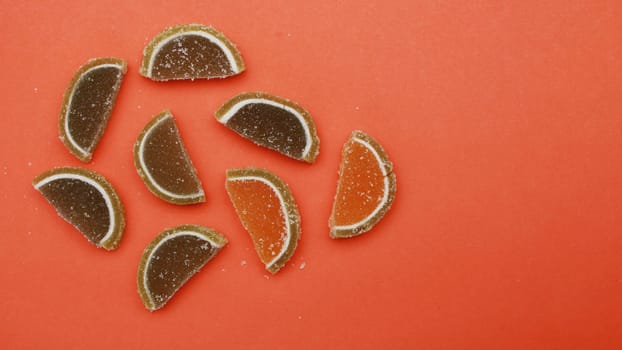 Flat lay of semicircular pieces of marmalade, gelatin candies on a background of red paper. Green and red pieces of marmalade. pieces of marmalade lie on a paper background;