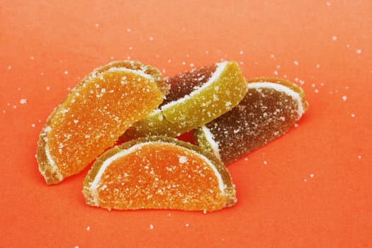 A bunch of four slices of red and green marmalade on a red background, close-up.