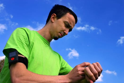 Sporting boy training with the chronometer and the mp3 player during a sunshine day