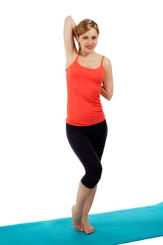 Pretty sportswoman stretching in front of white background