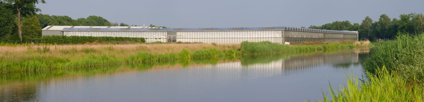 panoramic shot of a greenhouse next to a canal