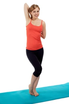 Young sportswoman on a fitness mat stretching against white background