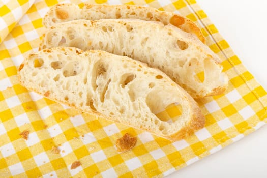 Three slices of ciabatta bread on a checkered tablecloth
