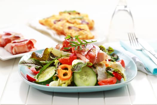 Big vegetable salad with prosciutto cheese rolls