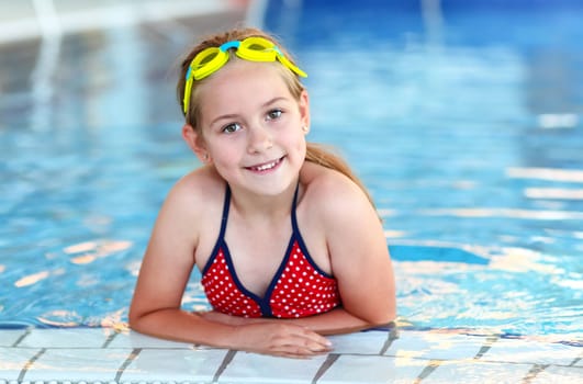 Cute girl with goggles in swimming pool