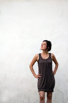 young woman on a plain wall looks pensive