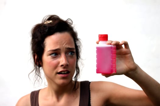 young woman looking critical at a red fluid in a plastic bottle