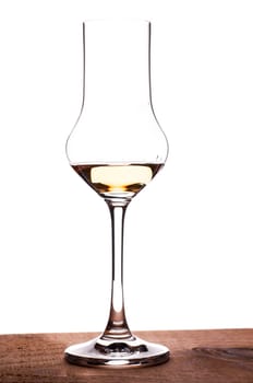 Glass of grappa standing on a wooden board in backlight