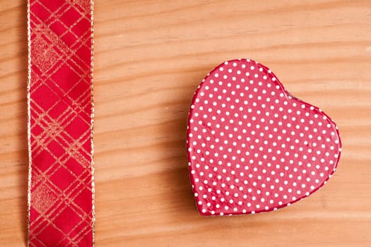 Red heart and gold-red ribbon on a wooden board