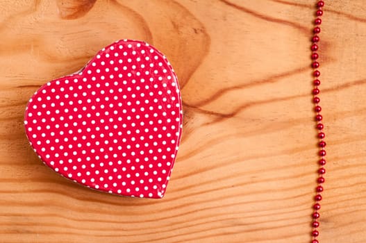 Red heart and pearl necklace on a wooden board
