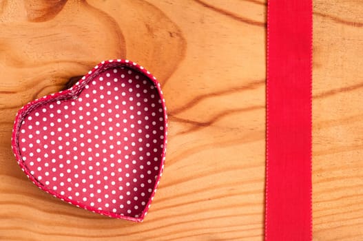 Open red heart and ribbon on a wooden board