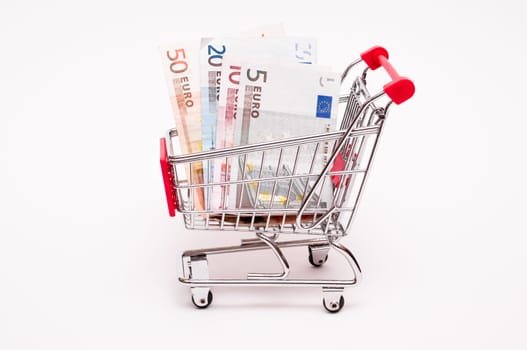 Euro bills in a shopping cart against white background