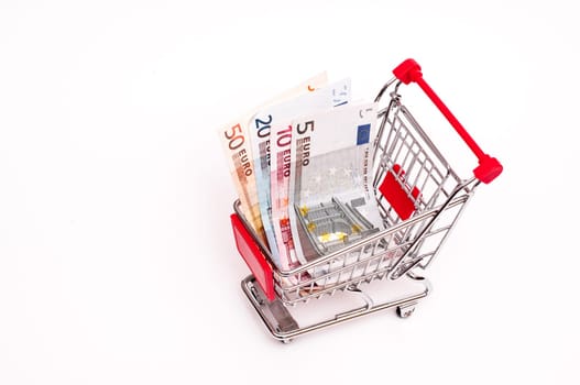 Banknotes in shopping cart on white background