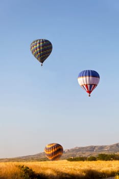 Colourful hot air ballonns rising over the ridge. A generic portrait was taken early morning in Cappadocia, Turkey.
