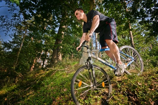 Downhill mountain bike rider in wooded environment and side view