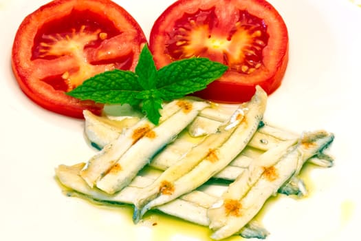 ration of anchovies in vinegar, garnished with tomato and mint