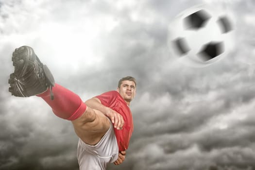 Young soccer player kicks a ball in front of dramatic sky