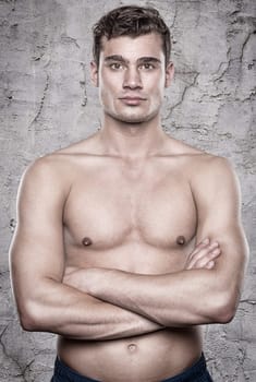 Young shirtless man in front of a stone wall