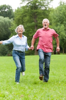 Active retired couple jumping in a park