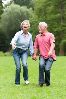 Active retired couple jumping in a park