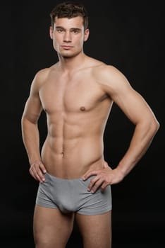 Young shirtless man against black studio background