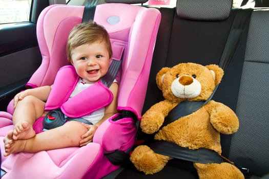 baby girl with his teddy bear smile in car