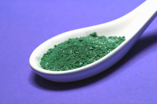 poisoned colored spice on a porcelain spoon