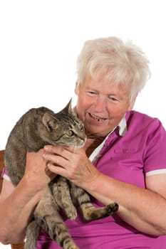 Happy grey-haired retired lady smiling as she holds her alert cat in both hands isolated on white