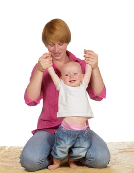 Cute baby with a wide grin learning to walk as its mother holds and supports it by the arms