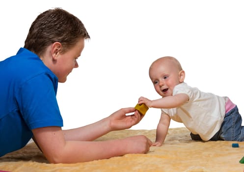 Happy inquisitive baby playing with Dad on the floor reaching out to grab an educational wooden block in a spontaneous gesture