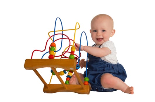 Happy cute baby playing on the floor with a wooden educational toy with looped wires for teaching coordination and colours isolated on white