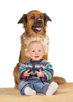 Happy smiling little baby sitting on the floor under the watchful eye of the trusted family dog